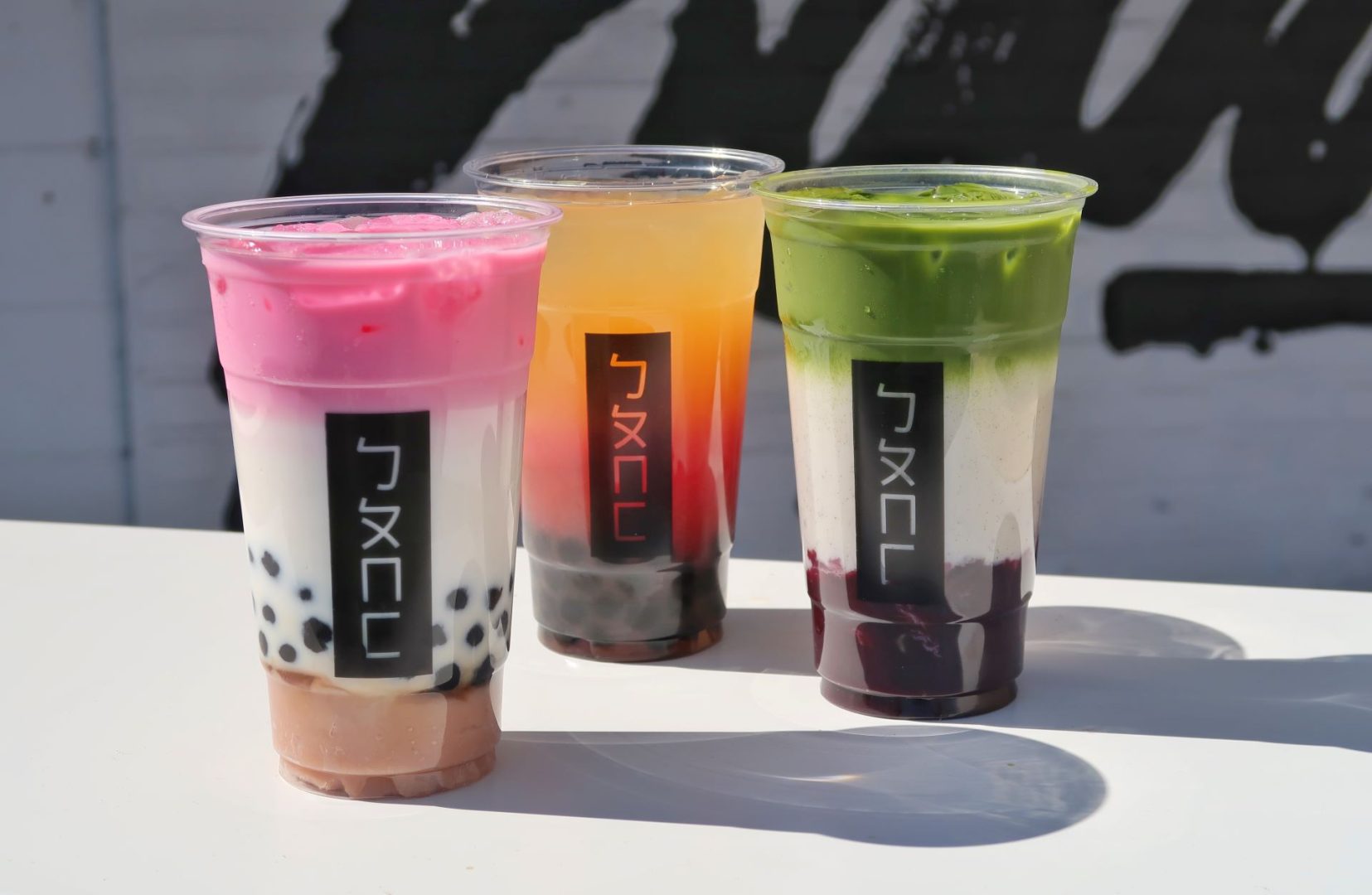 Three Bopo Go boba drinks on a white tabletop