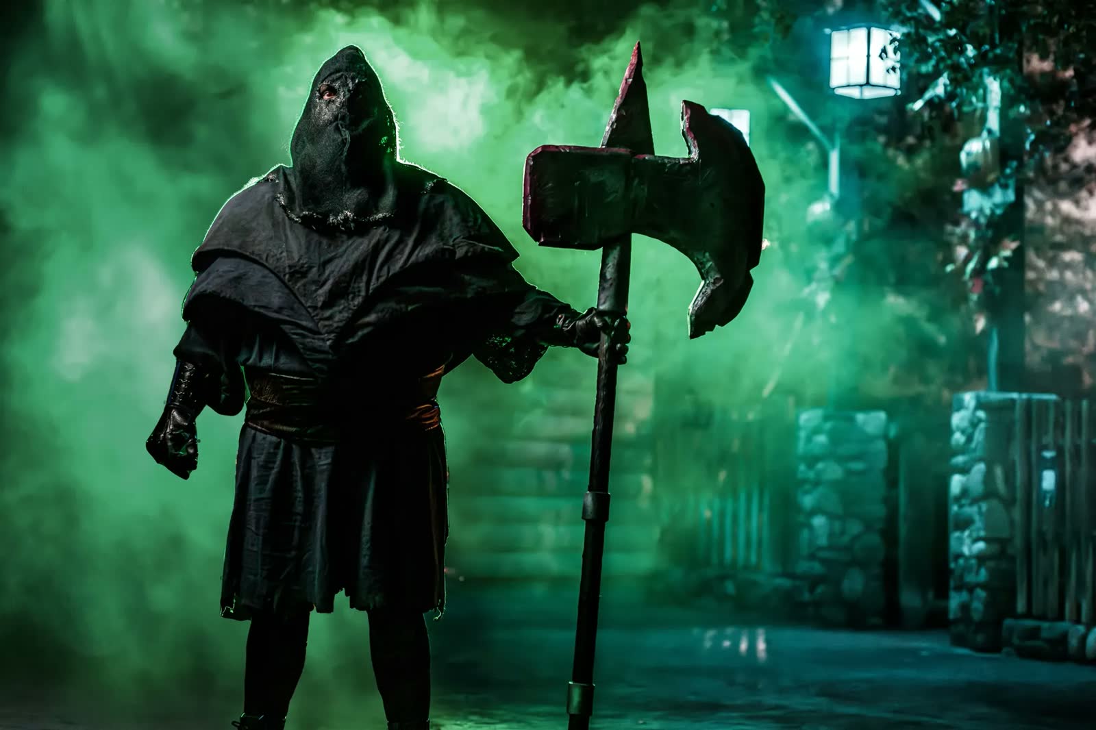 Hooded Knott's Scary Farm performer holding an axe in green fog