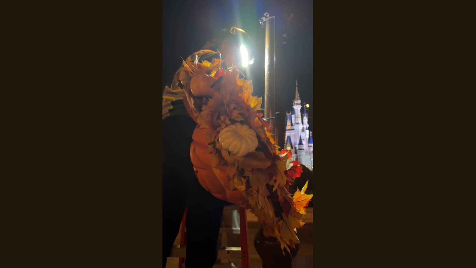 A cast member installs a Mickey pumpkin wreath at Magic Kingdom