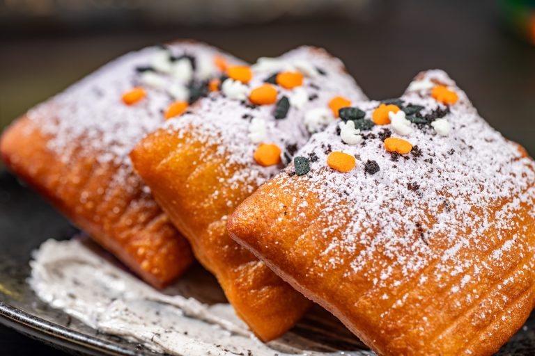 Beignets from Beyond: Light, sweet, and fluffy beignets with powdered sugar and chocolate cookie pieces over cookies and cream cheese icing (Available during Mickey’s Not-So-Scary Halloween Party only)
