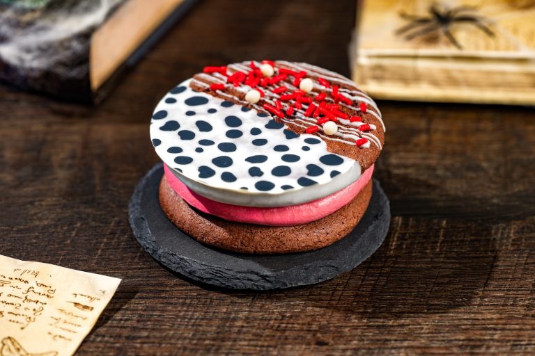 Cruella Cookie Sandwich: Chocolate cookies filled with raspberry ganache dipped in white chocolate and sprinkles (New) (Available during Mickey’s Not-So-Scary Halloween Party only)