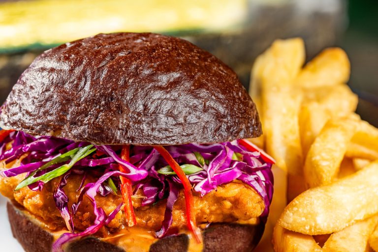 Devilish Crispy Chicken Sandwich: Ghoulish spiced mayonnaise, red cabbage, and Fresno peppers on a black kaiser roll served with french fries (New) (Available during regular park hours and Mickey’s Not-So-Scary Halloween Party; reservations recommended)