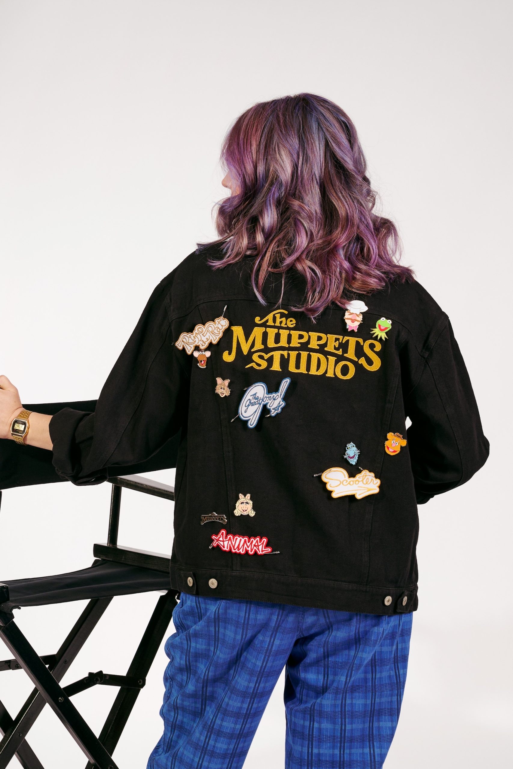 Back of a black Muppets denim jacket covered with character pins and patches