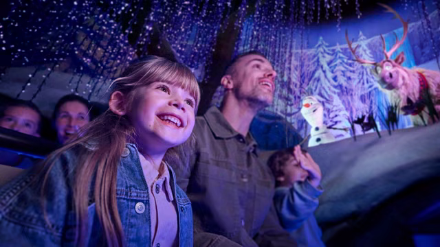 Guests ride Frozen Ever After at Disneyland Paris with Olaf and Sven nearby