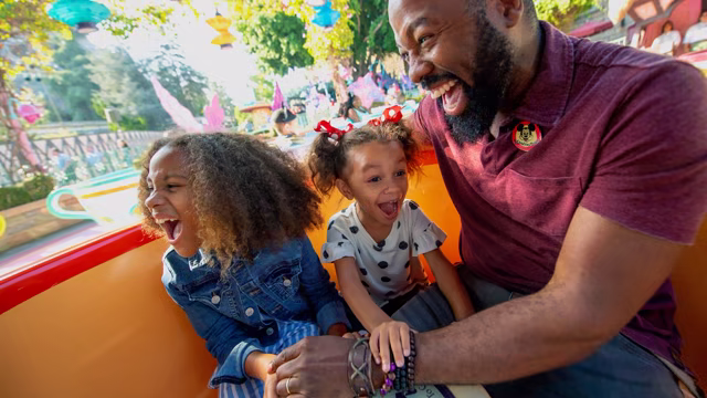 A father and two daughters ride Mad Tea Party at Disneyland