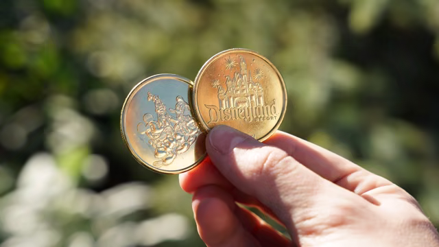 Official Disneyland photo of two collectible medallions from the wider resort program.
