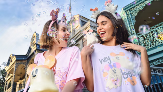 Two guests model Disneyland Halloween merchandise from the Disney Pastel Ghost Collection