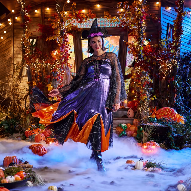 Adult Minnie Mouse witch costume with a purple dress and spiderweb cape.