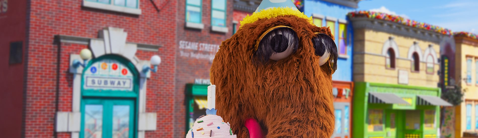 Snuffy wears a birthday hat and holds a cupcake at Sesame Place Philadelphia