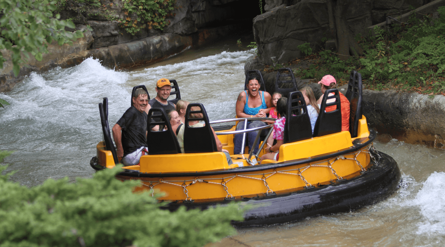 A yellow Roaring Rapids raft carrying guests through the water at Six Flags Great America