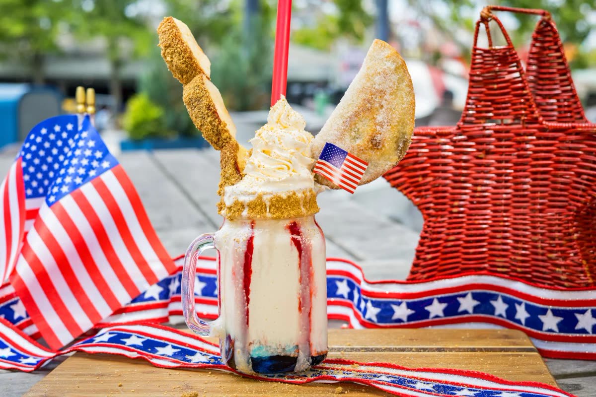 Apple pie milkshake with red and blue syrup, whipped cream, and fried apple skewers