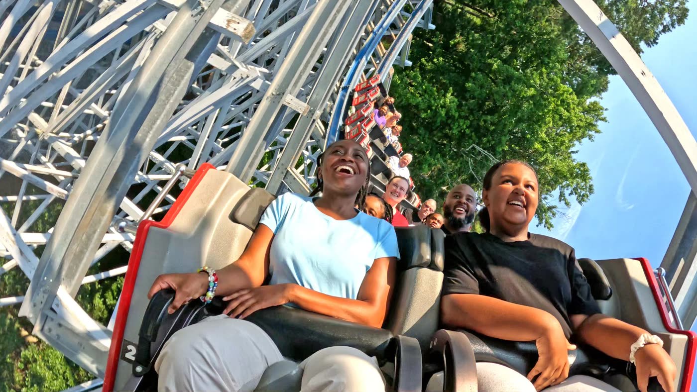 A coaster train banks through a loop on a sunny day at a Six Flags amusement park