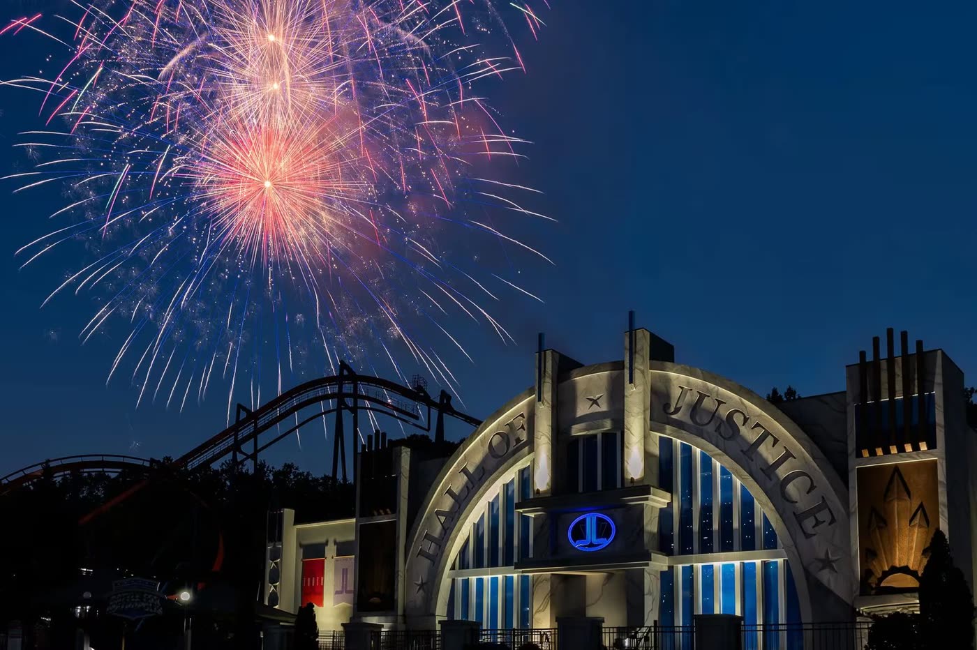 Fireworks burst over a blue-lit tower at a Six Flags America 250 celebration