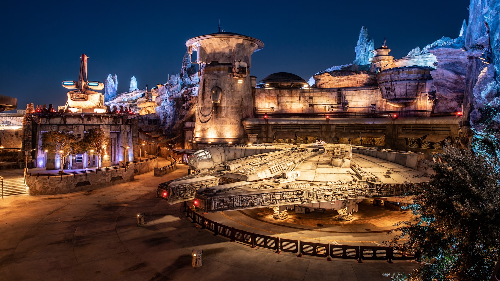 The Millennium Falcon parked outside Ohnaka Transport Solutions at night in Star Wars: Galaxy's Edge