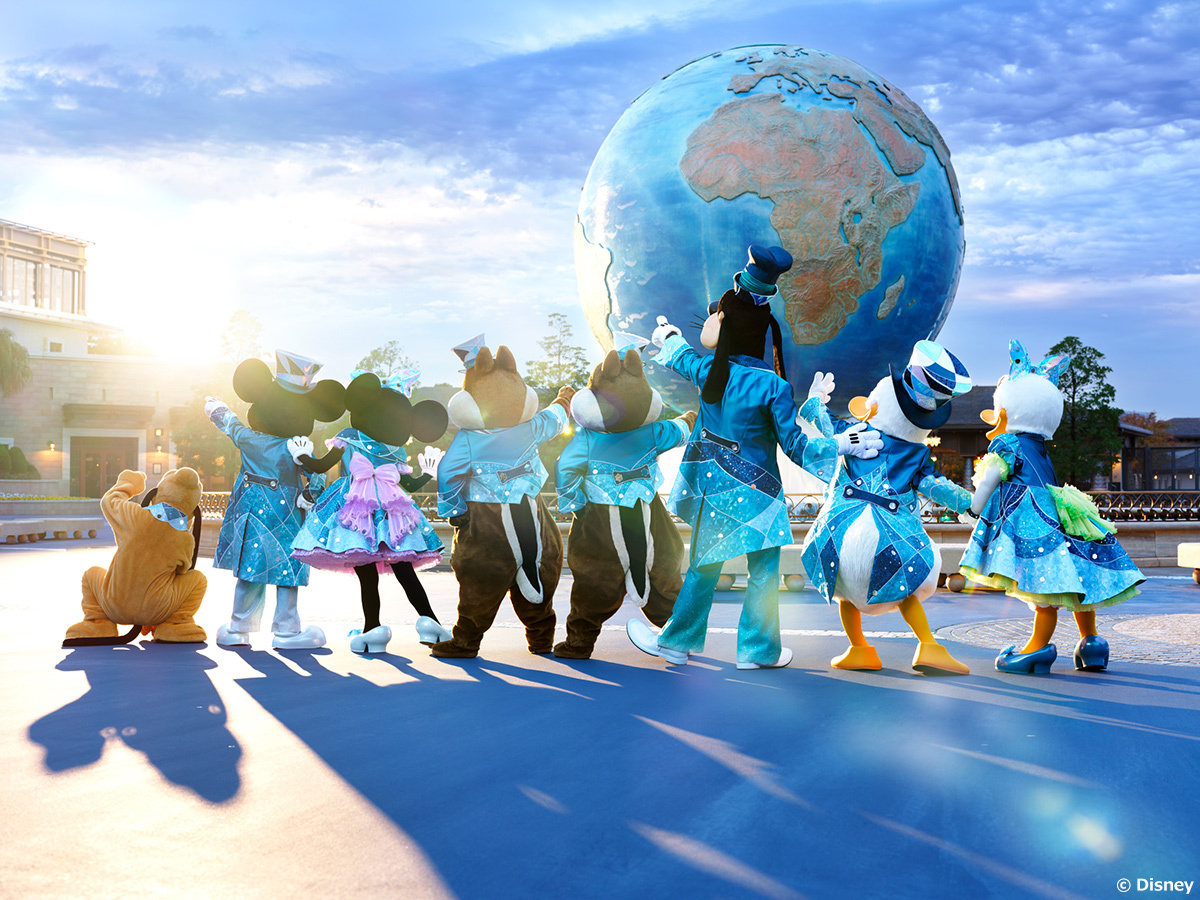 Mickey Mouse and friends in blue anniversary costumes facing the Aquasphere at Tokyo DisneySea