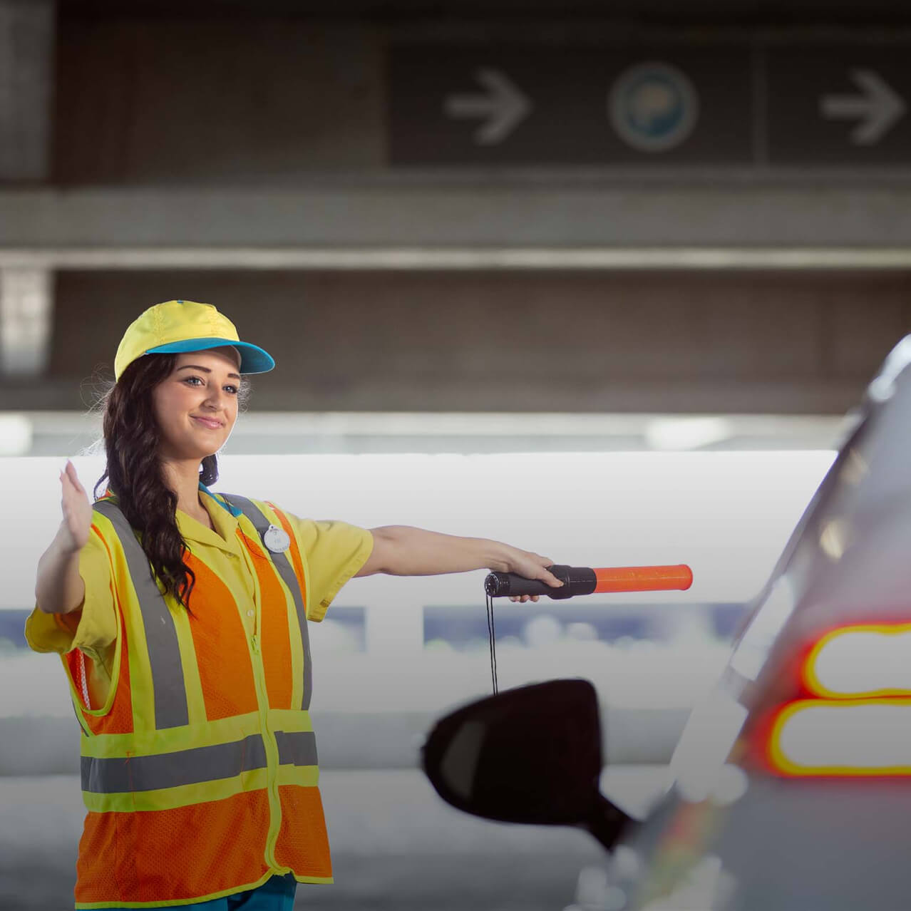 A Universal Orlando parking team member directs a car inside a resort garage