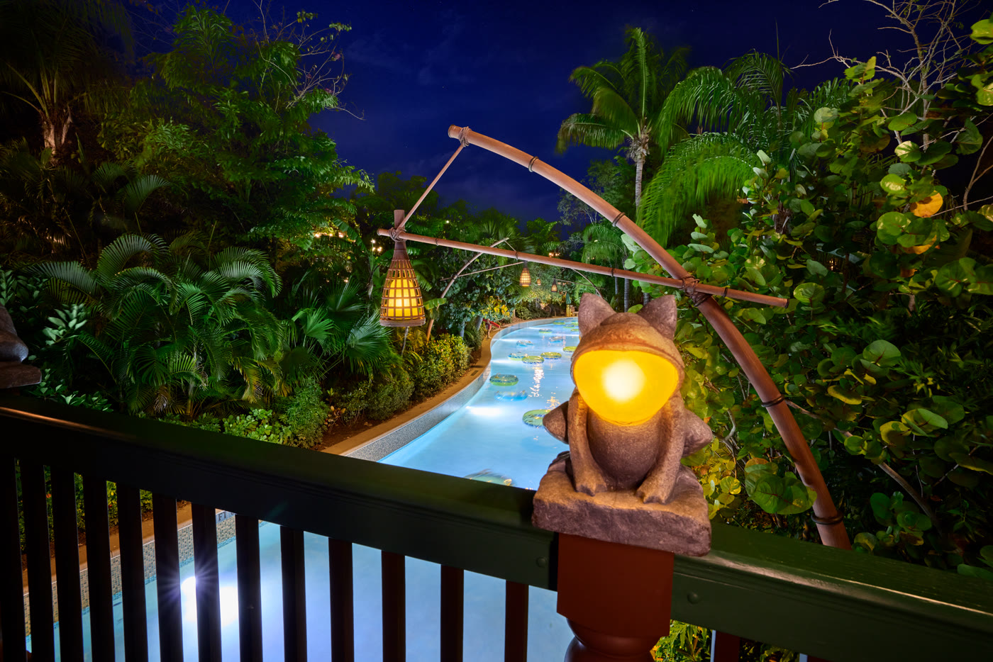 Night view of a Volcano Bay lazy river and tropical landscaping