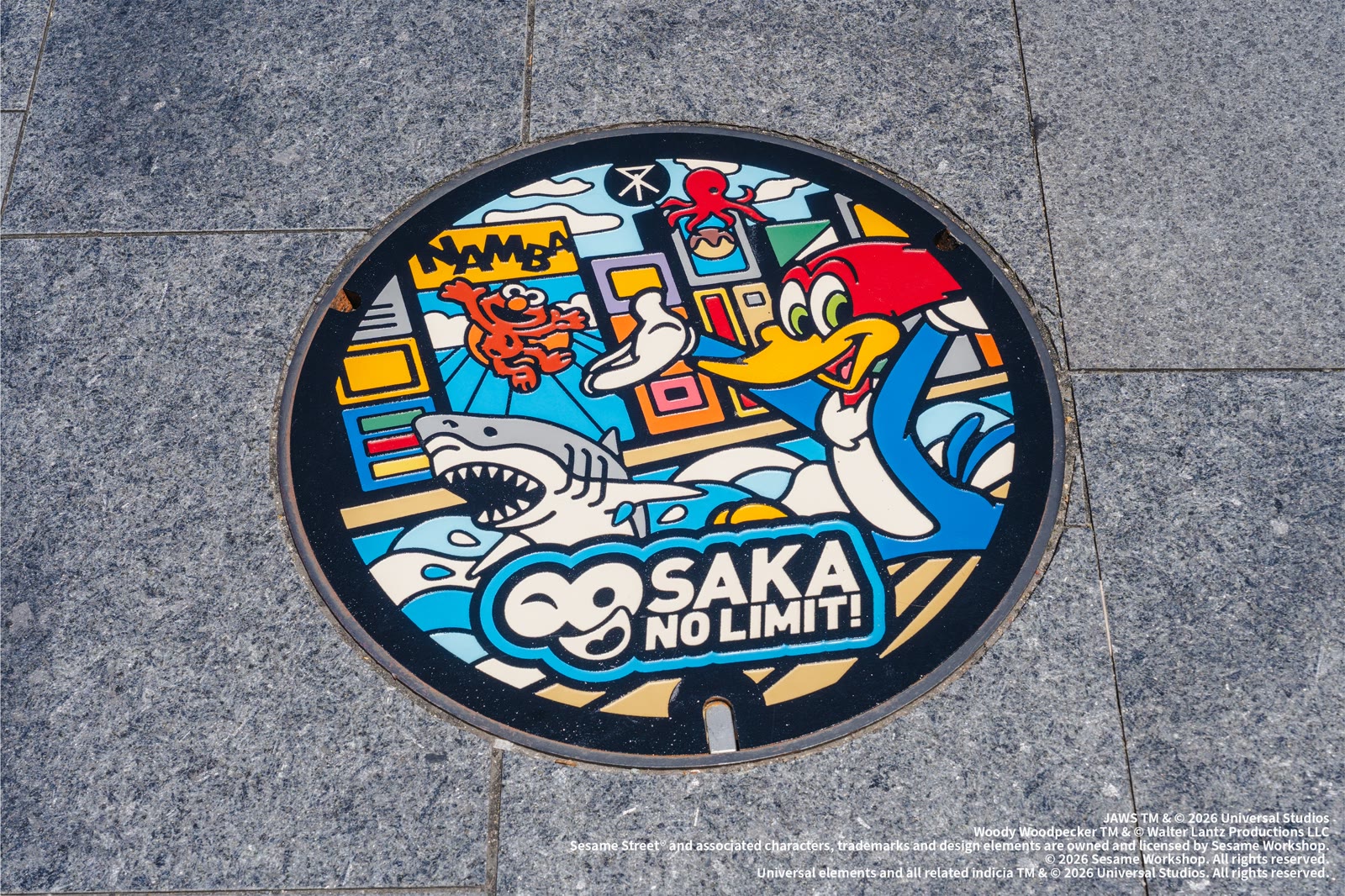 Universal Studios Japan 25th anniversary manhole cover with Woody Woodpecker, Jaws, and Osaka artwork