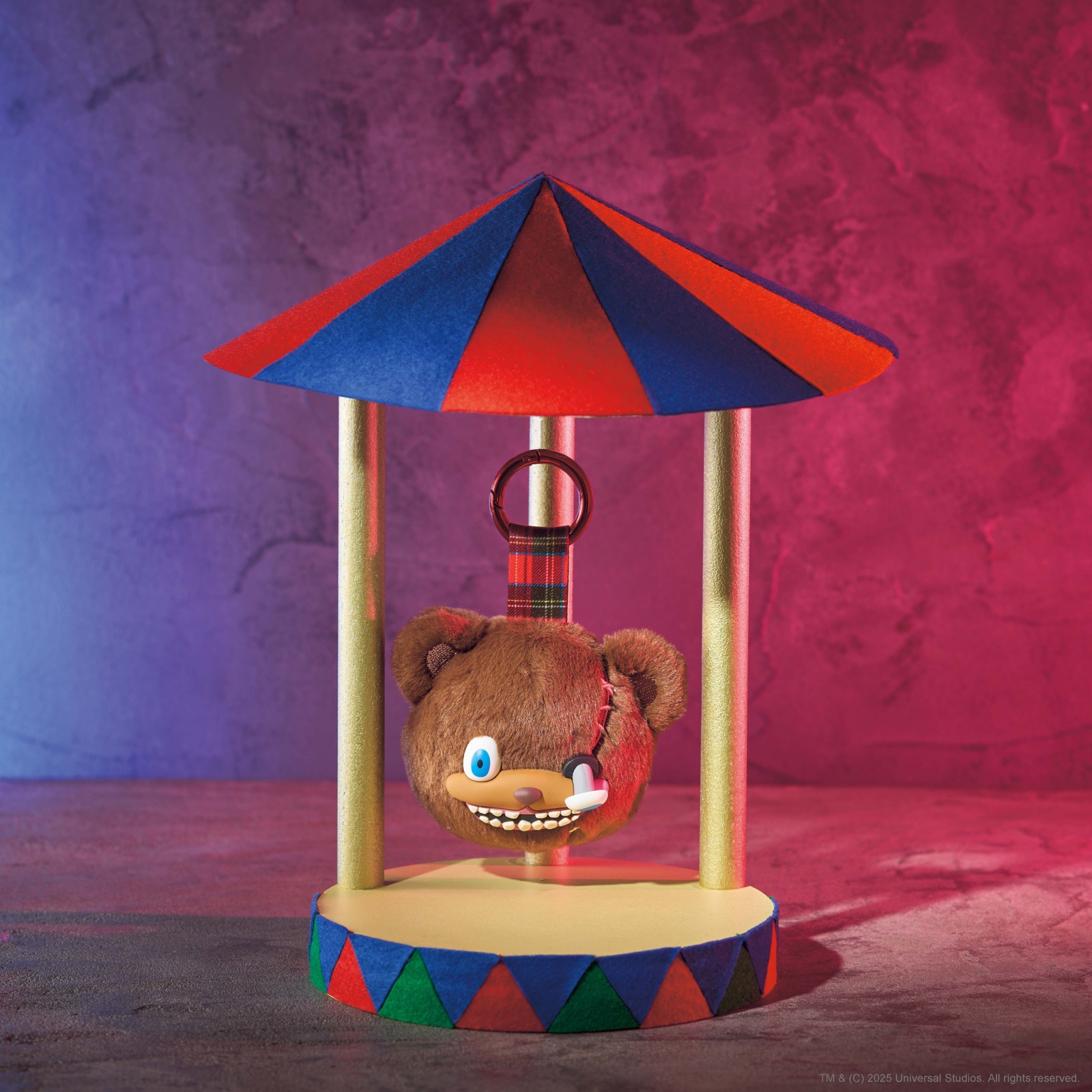 HamiKuma face keychain displayed beneath a striped carnival canopy